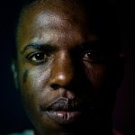 Dramatic close-up portrait of a man with artistic lighting emphasizing expression.